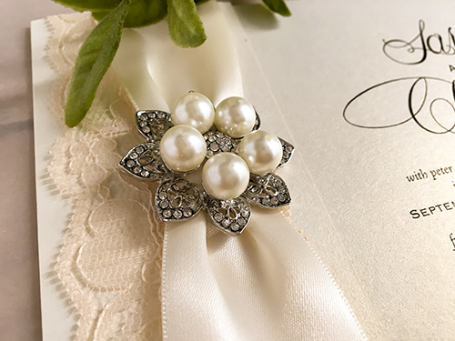 Invitation 2125: White Gold, Antique Ribbon, Cream Lace, Brooch/Buckle T - This is a folded over white gold pearl wedding invite.  There is an antique ribbon, cream lace and brooch on the design.
