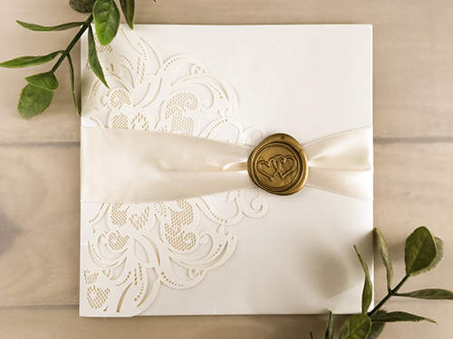 Invitation lc134: Ivory Shimmer, Cream Smooth, Gold Wax, Antique Ribbon - This is an ivory shimmer laser cut pocket folder wedding invite.  There is an antique ribbon with a gold double heart wax seal.