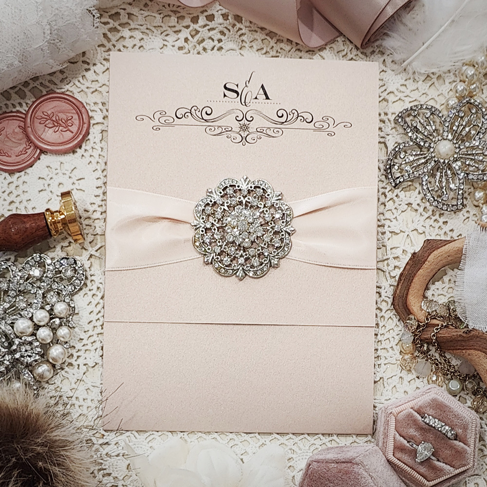 Invitation 3505: Blush Pearl, Blush Ribbon, Brooch/Buckle A20 - Pocketfolder wedding invitation on blush pearl with a blush ribbon and large brooch.
