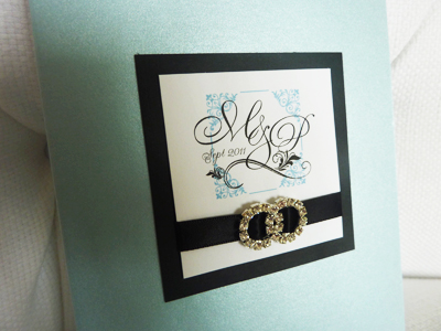 Invitation 915: Blue Aspire Pearl, Black Linen, White Smooth, Devon, Copperplate, Black Ribbon, Brooch/Buckle C