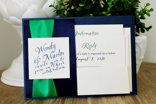 Invitation 1502: This is a navy single pocket invite where the navy pearl paper is folded on the right side to create a pocket which holds the invitation wording card.  A thick emerald ribbon and two navy ribbons are wrapped around the pocket flap.