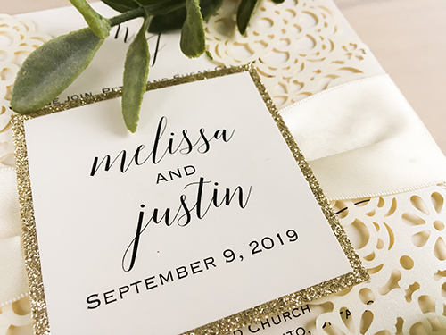 Invitation lc124: Ivory Shimmer, Champagne Glitter, Cream Smooth, Antique Ribbon - This is an ivory shimmer gate fold laser cut wedding design.  There is an antique ribbon with a champagne glitter layered cover tag.