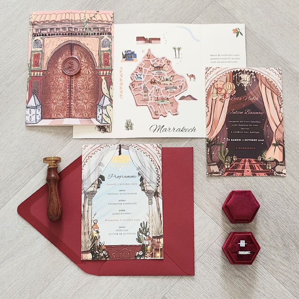 This is a gatefold style wedding invitation printed on a ivory off white paper.  There is a blush wax seal embellished on the cover of the invite.  There were 2 full color inserts included in this suite.
An illustration of the area where the wedding is taking place is printed on the cover of the invites like you are opening the large gates to the Marrakesh markets.  Inside there is a map of the city showcasing the important parts of the city for guests to experience.
This wedding took place in Marrakesh, Morocco.
Marrakesh is one of Morocco’s most enchanting wedding destinations, offering a blend of rich history, vibrant colors, and exotic romance. Here’s an overview to help you imagine a wedding there.
Atmosphere & Scenery: With its terracotta walls, palm-fringed gardens, and views of the snow-capped Atlas Mountains, Marrakesh provides a dramatic backdrop for ceremonies and photography. The city’s mix of ancient medina alleyways, ornate riads, and opulent palaces brings a “1001 Nights” feel.
Venues: Couples often marry in luxurious riads (traditional courtyard homes), grand private villas, or historic palaces such as Palais Namaskar or La Mamounia. Desert-style venues on the outskirts of the city—like Agafay Desert camps—create a magical, star-filled evening atmosphere. This is a gatefold style wedding invitation printed on a ivory off white paper.  There is a blush wax seal embellished on the cover of the invite.  There were 2 full color inserts included in this suite.
An illustration of the area where the wedding is taking place is printed on the cover of the invites like you are opening the large gates to the Marrakesh markets.  Inside there is a map of the city showcasing the important parts of the city for guests to experience.
This wedding took place in Marrakesh, Morocco.
Marrakesh is one of Morocco’s most enchanting wedding destinations, offering a blend of rich history, vibrant colors, and exotic romance. Here’s an overview to help you imagine a wedding there.
Atmosphere & Scenery: With its terracotta walls, palm-fringed gardens, and views of the snow-capped Atlas Mountains, Marrakesh provides a dramatic backdrop for ceremonies and photography. The city’s mix of ancient medina alleyways, ornate riads, and opulent palaces brings a “1001 Nights” feel.
Venues: Couples often marry in luxurious riads (traditional courtyard homes), grand private villas, or historic palaces such as Palais Namaskar or La Mamounia. Desert-style venues on the outskirts of the city—like Agafay Desert camps—create a magical, star-filled evening atmosphere.