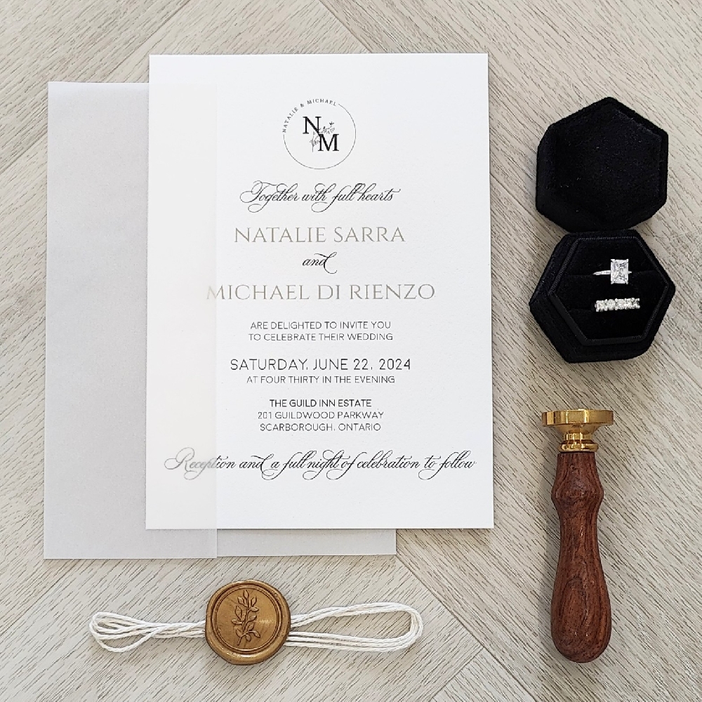 This is a single card wedding invitation printed on a white paper with black ink.  There is a full vellum wrap enclosure along with a white string and gold branch wax seal embellishment.   On the layout there is a custom monogram at the top with a mix of modern and classic fonts used throughout.
This wedding took place at the Guild Inn Estates in Scarborough, Ontario, Canada.
The Guild Inn Estate in Scarborough, Ontario, is one of the most unique wedding venues in the GTA. Located on 88 acres of parkland along the Lake Ontario shoreline, it combines historic charm with modern elegance. The estate is famous for its heritage architecture, sculpture gardens, and outdoor Greek-inspired ruins, which make for breathtaking photo backdrops. Couples who want both a natural and historic feel to their celebration often choose this venue.
The Guild Inn features multiple event spaces: a grand ballroom with floor-to-ceiling windows overlooking the gardens, elegant outdoor ceremony spaces surrounded by lush greenery, and smaller rooms for more intimate weddings. The modern renovations blend beautifully with the venue’s history, making it suitable for both classic and contemporary weddings. Guests also love the convenience of onsite parking, the proximity to Toronto, and the feeling of escaping into a serene retreat. This is a single card wedding invitation printed on a white paper with black ink.  There is a full vellum wrap enclosure along with a white string and gold branch wax seal embellishment.   On the layout there is a custom monogram at the top with a mix of modern and classic fonts used throughout.
This wedding took place at the Guild Inn Estates in Scarborough, Ontario, Canada.
The Guild Inn Estate in Scarborough, Ontario, is one of the most unique wedding venues in the GTA. Located on 88 acres of parkland along the Lake Ontario shoreline, it combines historic charm with modern elegance. The estate is famous for its heritage architecture, sculpture gardens, and outdoor Greek-inspired ruins, which make for breathtaking photo backdrops. Couples who want both a natural and historic feel to their celebration often choose this venue.
The Guild Inn features multiple event spaces: a grand ballroom with floor-to-ceiling windows overlooking the gardens, elegant outdoor ceremony spaces surrounded by lush greenery, and smaller rooms for more intimate weddings. The modern renovations blend beautifully with the venue’s history, making it suitable for both classic and contemporary weddings. Guests also love the convenience of onsite parking, the proximity to Toronto, and the feeling of escaping into a serene retreat.