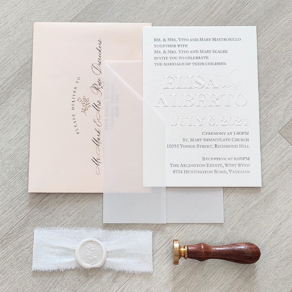 This is an exquisite luxurious set of invitations.  It is a vintage raised blind embossed main card on a white cotton paper.  There is a special cut full vellum wrap along with a white lace and white wax seal embellishment.  This set goes into a blush shimmer envelope.  You can see that the names of the couple uses a raised blind embossing printing method.
This wedding took place at the Arlington Estates in Vaughan, Ontario.
Blind embossing wedding invitations are a sophisticated and timeless option for couples who want a luxurious, tactile design without the use of ink or foil. This printing technique creates a raised impression on the paper — adding depth, texture, and elegance that guests can literally feel. This is an exquisite luxurious set of invitations.  It is a vintage raised blind embossed main card on a white cotton paper.  There is a special cut full vellum wrap along with a white lace and white wax seal embellishment.  This set goes into a blush shimmer envelope.  You can see that the names of the couple uses a raised blind embossing printing method.
This wedding took place at the Arlington Estates in Vaughan, Ontario.
Blind embossing wedding invitations are a sophisticated and timeless option for couples who want a luxurious, tactile design without the use of ink or foil. This printing technique creates a raised impression on the paper — adding depth, texture, and elegance that guests can literally feel.