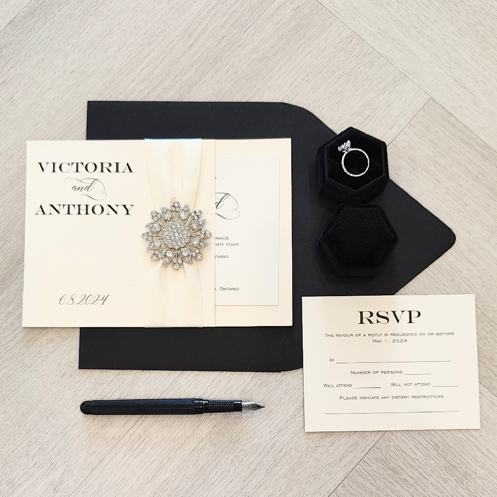 Pocket invite with a ribbon and brooch detail on the folder.  Paired with a black envelope.