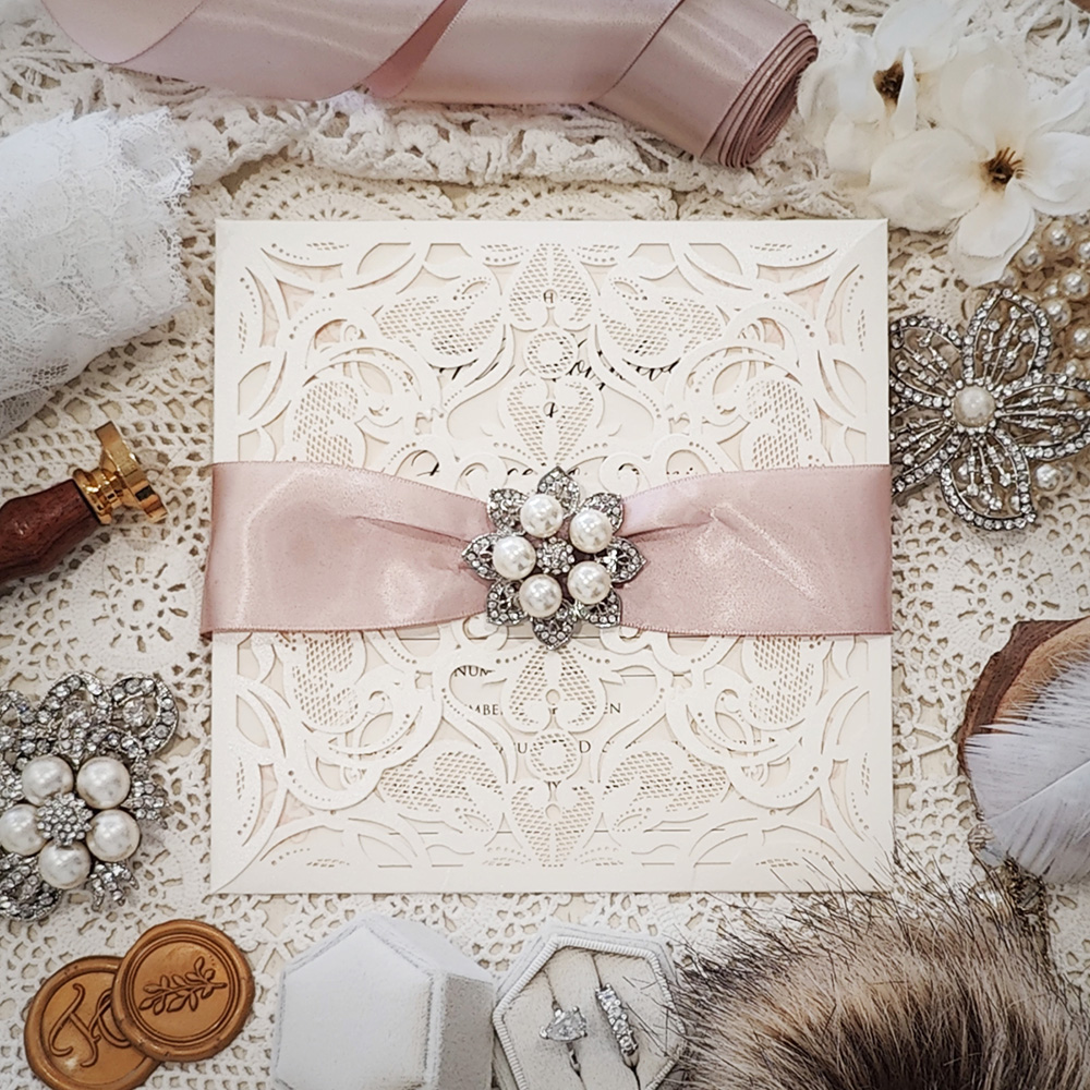 Invitation 3504: Ivory Shimmer, Cream Smooth, Deep Blush Ribbon, Brooch/Buckle T - This is a laser cut 4 flap wedding design with a ribbon and brooch detail.