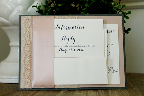 Invitation 1526: This invite has multiple layers and a unique pocket.  A lace and ribbon combination is wrapped around  charcoal and blush paper to create a pocket that will hold your invite card and reply card.