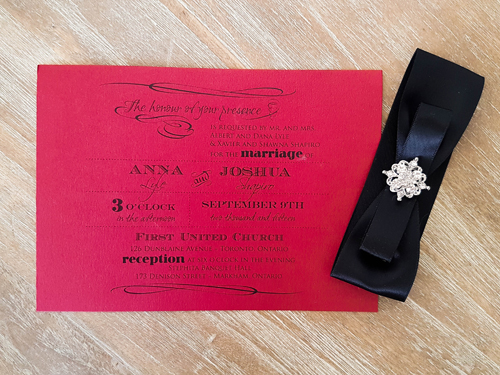 Invitation 1626: Red Lacquer, Red Lacquer, Black Ribbon, Black Ribbon, Brooch/Buckle A8 - This is a landscape orientation wedding invite on a red lacquer paper with a black ribbon and brooch no the right.