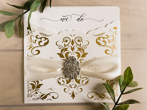 Invitation lc130: Ivory Shimmer, Cream Smooth, Antique Ribbon, Brooch/Buckle A17 - This is a gold foil printed laser cut pocket wedding invite.  There is an antique ribbon and brooch design.