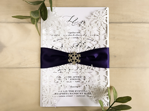 Invitation lc148: White Shimmer, Navy Ribbon, Brooch/Buckle A18 - This is a snow flake inspired white shimmer laser cut invitation design.  It is a gate fold.  There is a navy ribbon and snowflake brooch.