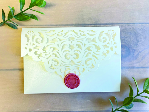 Invitation lc152: Ivory Shimmer, Cream Smooth, Blush Wax - This is an ivory shimmer pocket folder style laser cut wedding invitation.  There is a blush wax seal design on the flap.