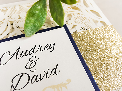 Invitation lc18: This is four flap laser cut wedding card in the ivory shimmer paper.  The belly band wrapped around is gold glitter with a navy pearl layered cover tag.