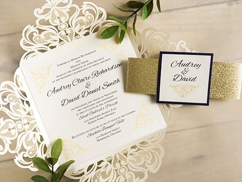 Invitation lc18: This is four flap laser cut wedding card in the ivory shimmer paper.  The belly band wrapped around is gold glitter with a navy pearl layered cover tag.