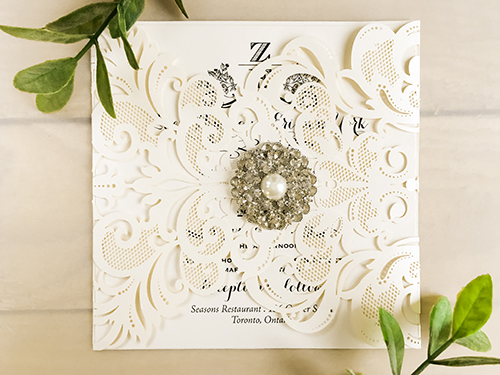 Invitation lc24: Ivory Shimmer, Cream Smooth, Brooch/Buckle A6 - This is a damask pattern gate fold laser cut wedding invite in the ivory shimmer paper.  There is a pearl and rhinestone brooch on the flap.
