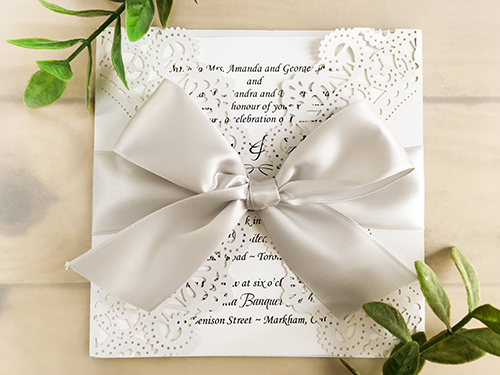 Invitation lc37: White Shimmer, White Smooth, Silver Ribbon - This is a white shimmer laser cut pattern wedding card design.  There is a large silver bow tied around the invitation.