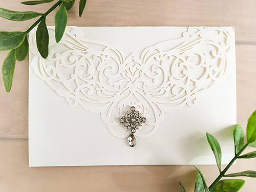 Invitation lc46: White - This is white colored laser cut wedding invitation.  There is a small brooch glued to the cover flap.