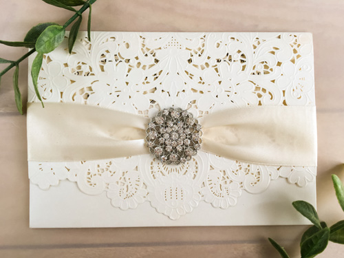 Invitation lc52: White, Cream Smooth, Antique Ribbon, Brooch/Buckle X - This is a pocket style laser cut wedding invitation in the white color.  There is an antique ribbon with rhinestone brooch on the flap.