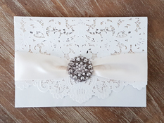 Invitation lc52: White, Cream Smooth, Antique Ribbon, Brooch/Buckle X - This is a pocket style laser cut wedding invitation in the white color.  There is an antique ribbon with rhinestone brooch on the flap.
