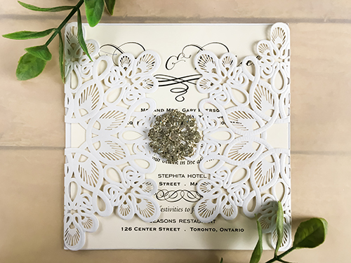 Invitation lc55: Glittering White, Cream Smooth, Brooch/Buckle A17 - This is a glittering white laser cut wedding invitation.  There is a rhinestone brooch glued to the middle.