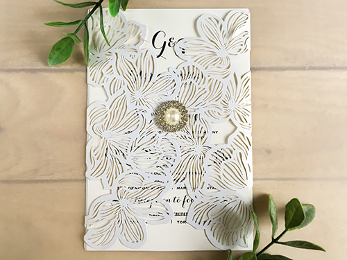 Invitation lc63: White Shimmer, Brooch/Buckle G - This is a white shimmer gate fold laser cut wedding invite.  The pattern is florals on flaps.  There is a pearl brooch on the middle.