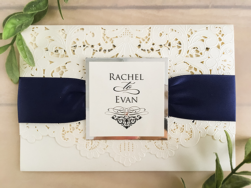 Invitation lc64: Ivory Shimmer, Silver Mirror, Cream Smooth, Brooch/Buckle Rhinestone - This is an ivory shimmer pocket style laser cut wedding invitation.  There is a navy ribbon with a silver mirror layered cover tag design on the flap.