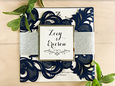 Invitation lc7: Baroque inspired laser cut wedding invitation in a deep glittering navy, with glitter wrap around belly band and a cover tag, backed with mirror paper.