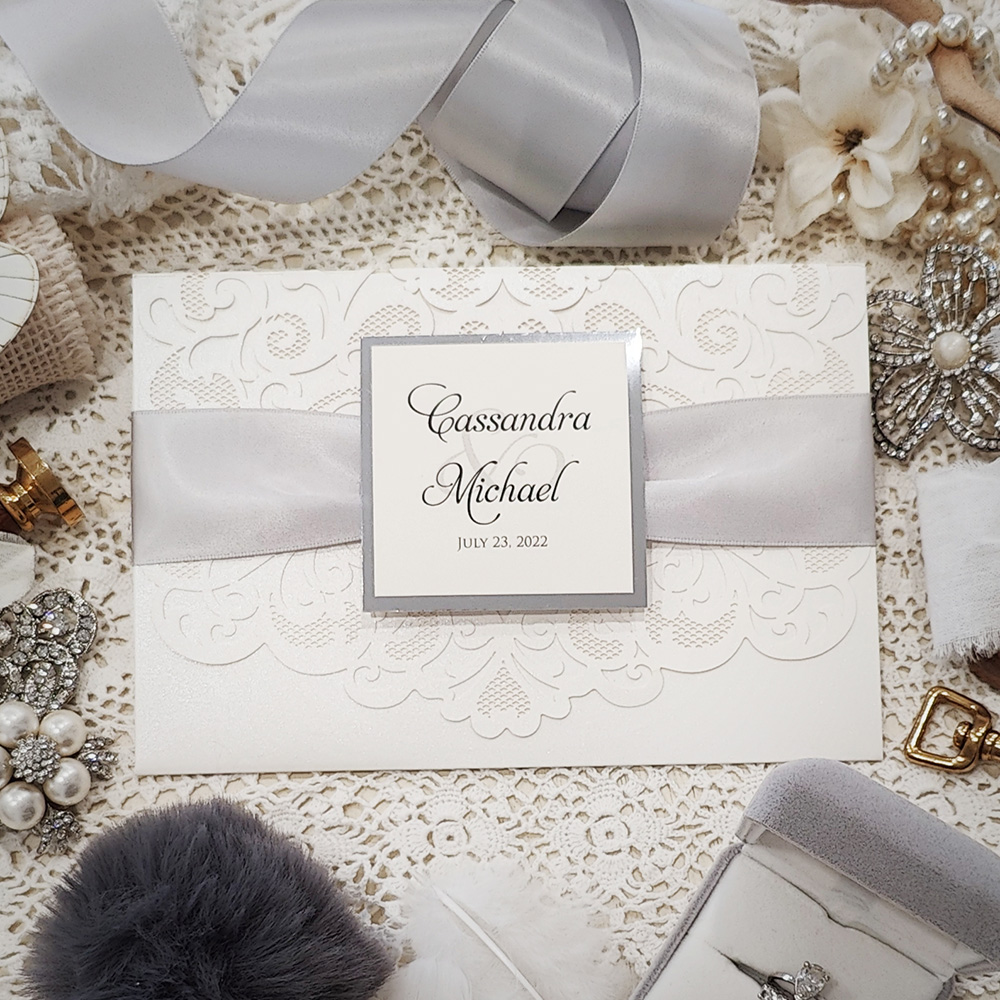 Invitation 8039: Ivory Shimmer, Silver Mirror, Cream Smooth, Silver Ribbon - Ivory pocketfold lasercut with ribbon and layered tag