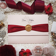 Invitation 3103: Rose Gold Pearl, Gold Wax, Sherry Ribbon - Landscape pocketfold wedding invitation opening vertically with a sherry ribbon and gold wax seal.