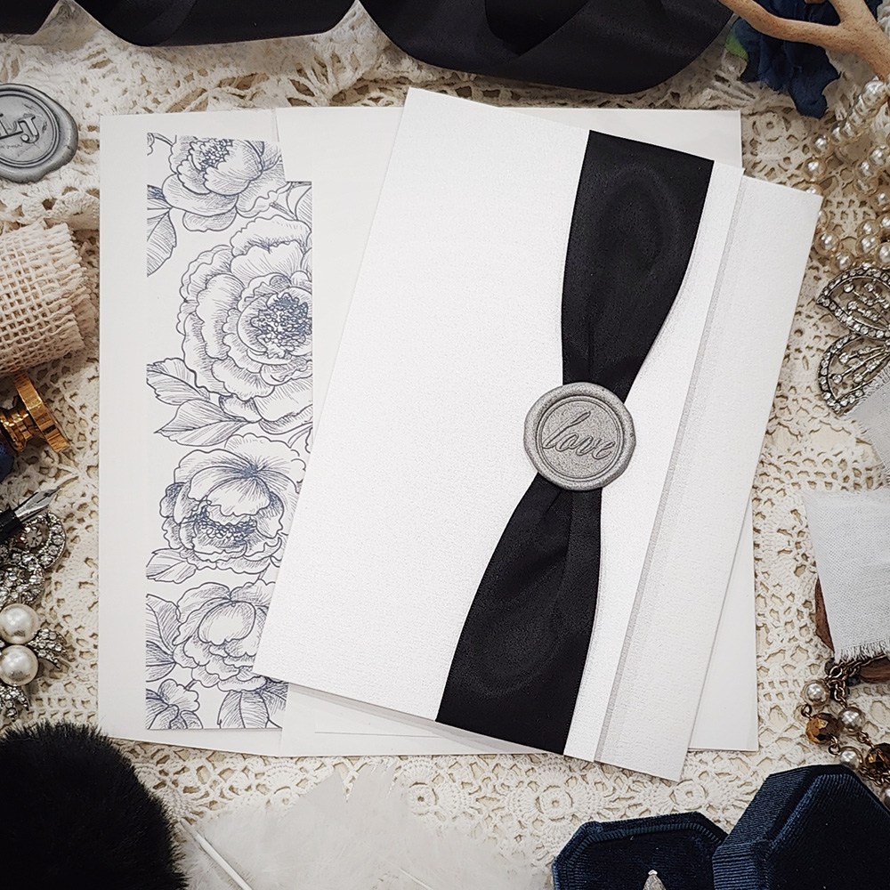 Invitation 3104: Ice Pearl, Silver Wax, Black Ribbon - Pocketfold wedding card in portrait layout opening horizontally.  Black ribbon and silver love wax seal.